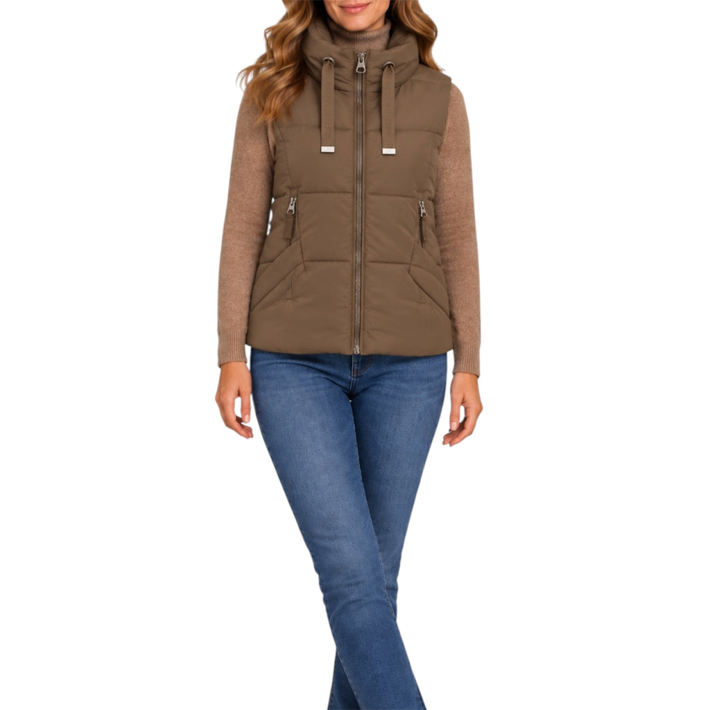 A woman wearing a brown hooded puffer vest over a tan long-sleeve top and blue jeans, shown against a plain white studio background.